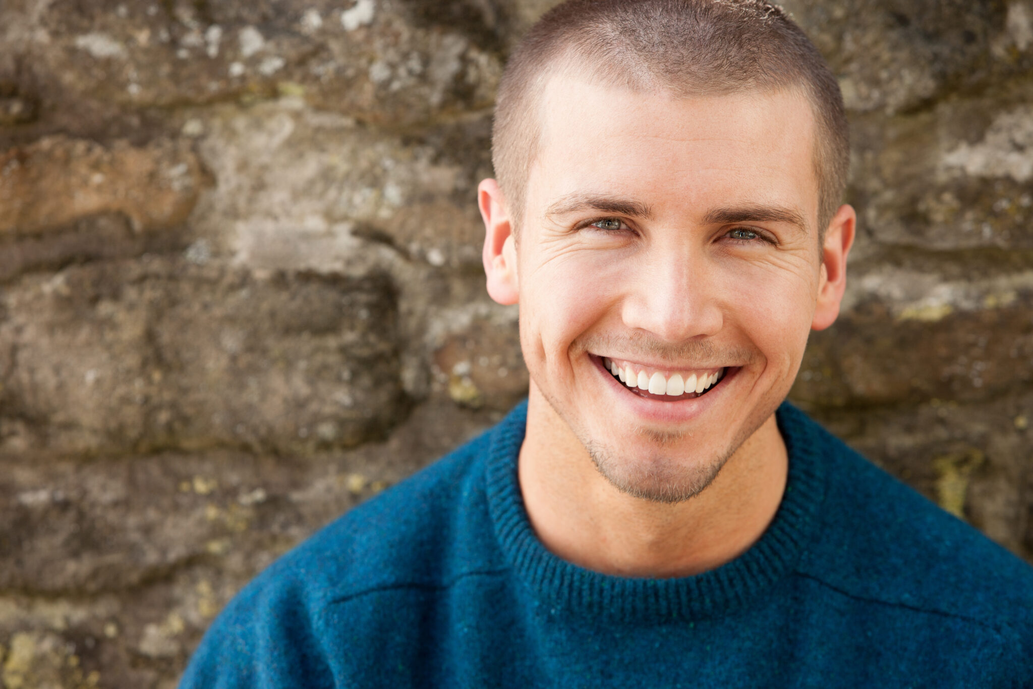 Man smiling against stone wall